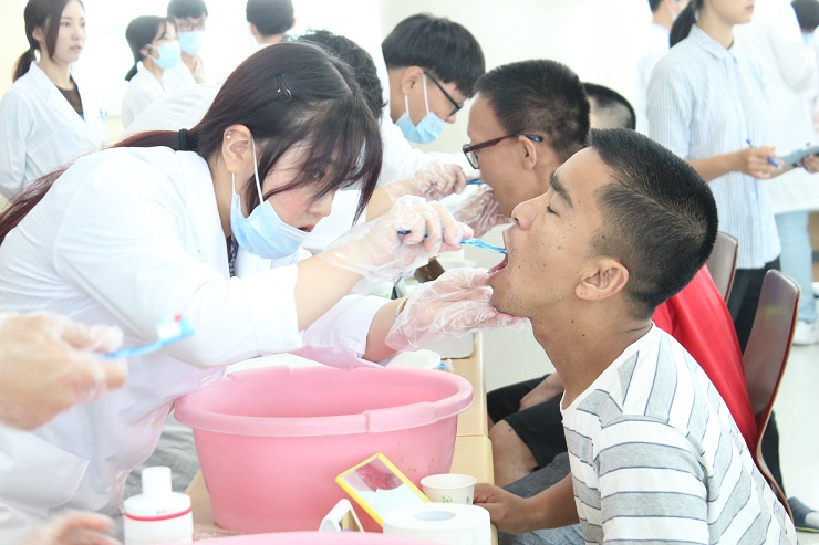 칫솔질 교육을 받고 있는 이용인과 교육 중인 치과대학 학생의 모습