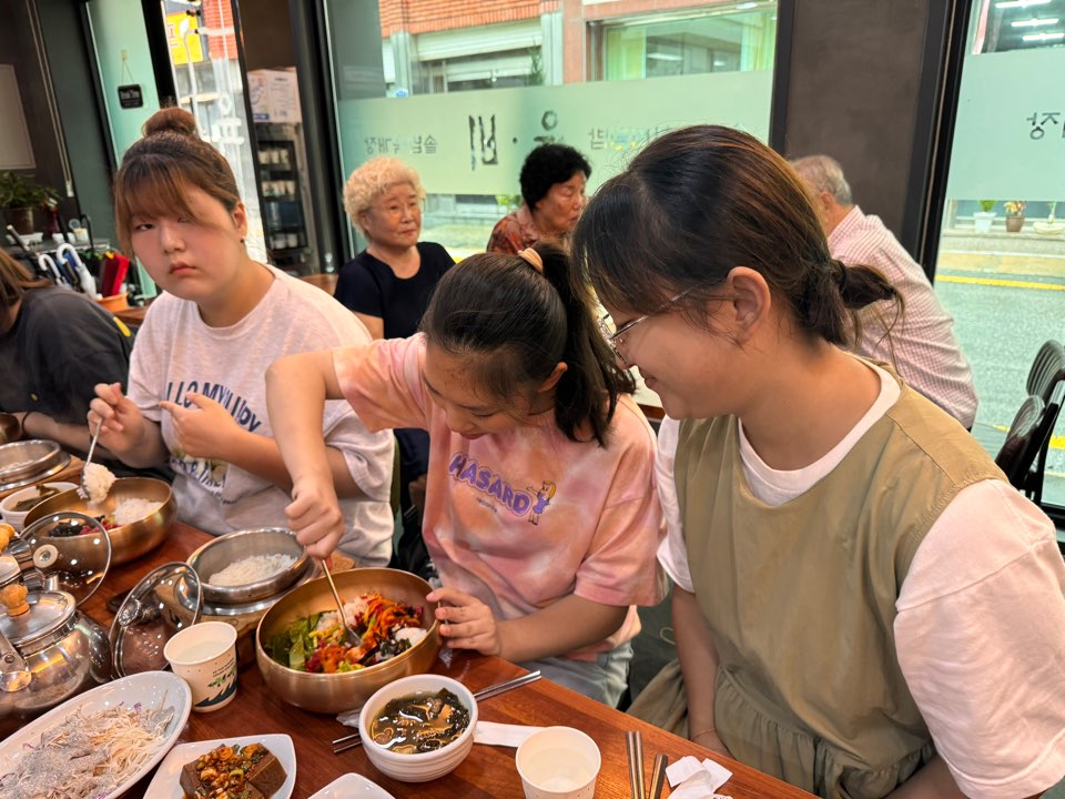 비빔밥을 비비고 있는 멘티를 다정하게 바라보고 있는 멘토의 모습입니다. 