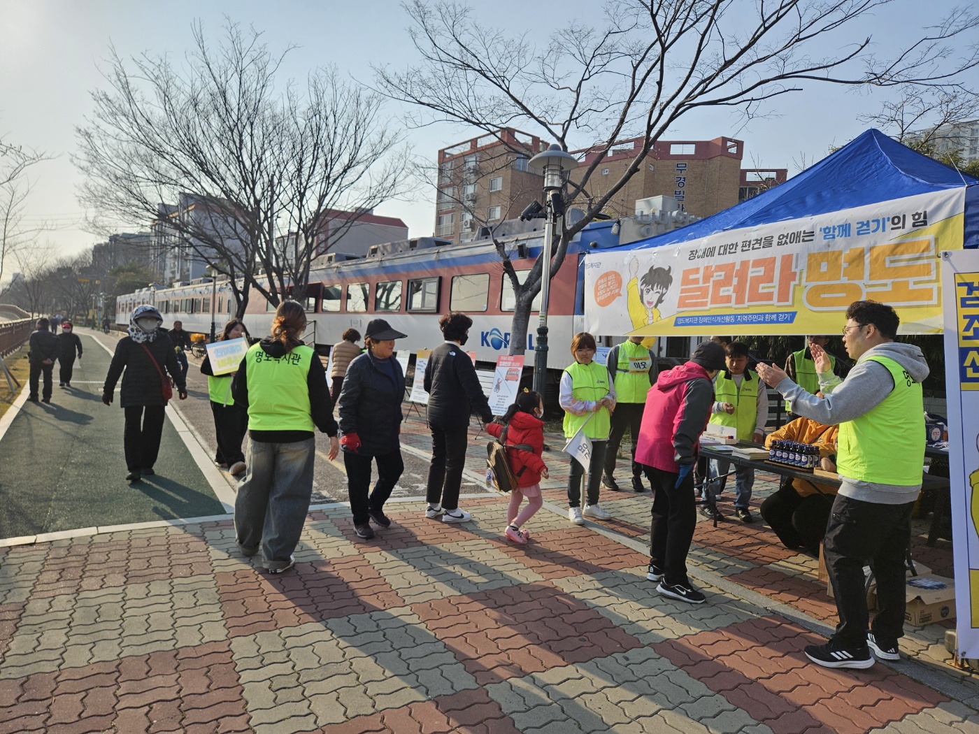 달려라명도 현수막이 걸린 천막을 중심으로 지역주민들이 모여들고 있는 모습의 사진입니다. 