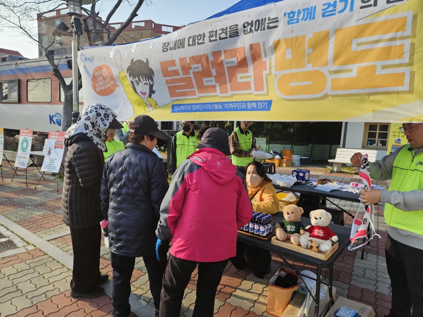 지역주민들이 홍보부스에 모여있고 담당직원이 사업을 설명하고 있는 모습의 사진입니다. 