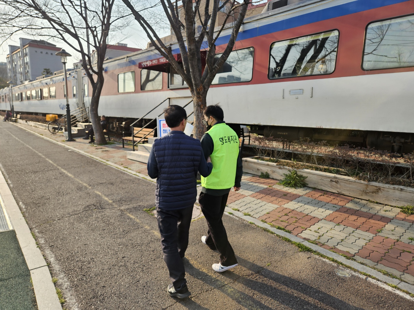 권리중심일자리 참여자가 지역주민과 함께 걷고 있는 모습의 사진입니다. 