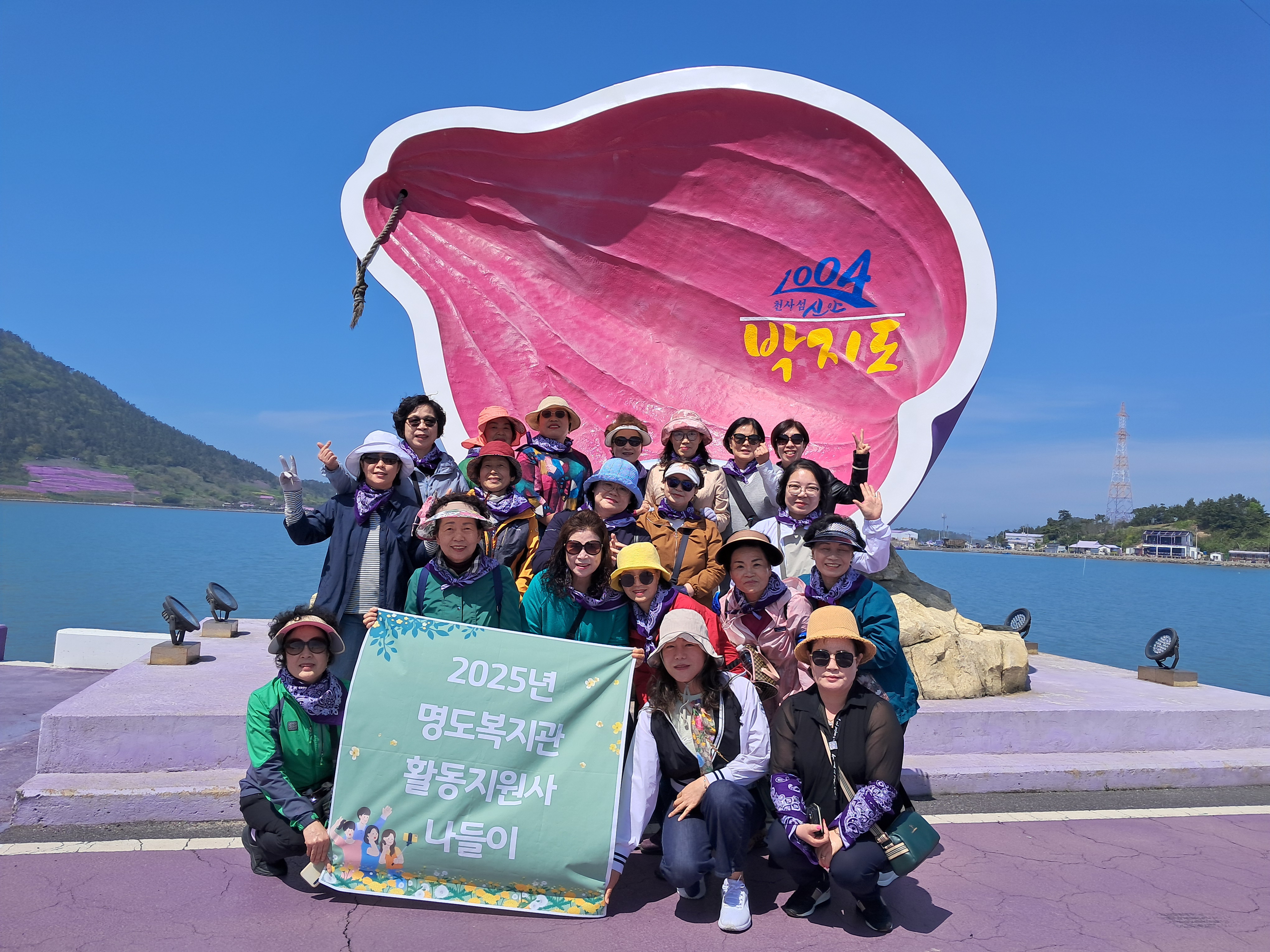 박지도를 나타내고 있는 조형물앞에서 2025년 명도복지관 활동지원사 나들이 현수막을 펴고 함께 찍은 단체사진입니다. 