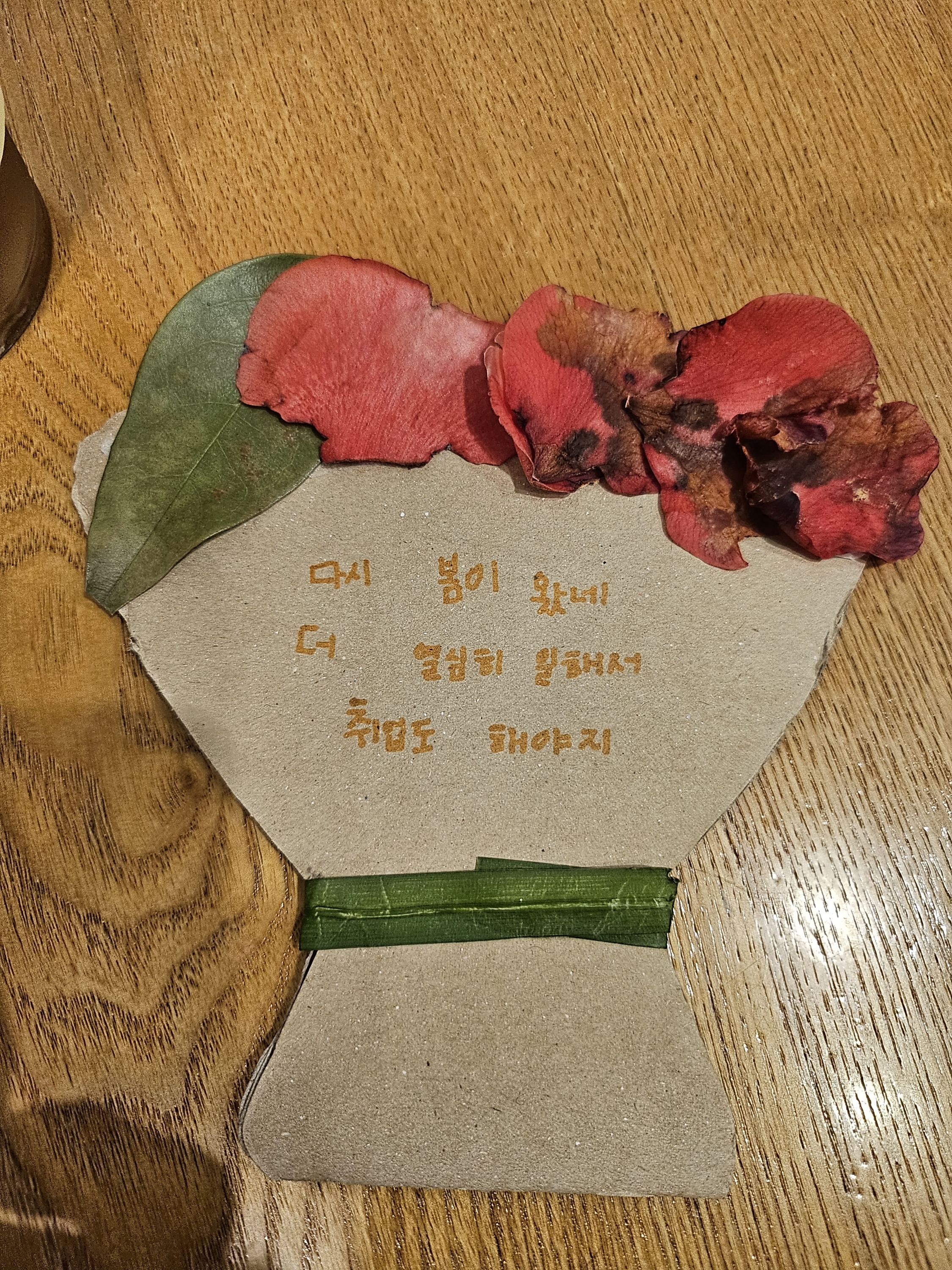 떨어진 꽃잎과 나뭇잎으로 종이화병을 꾸민 작품 사진입니다. 종이화병에는 다시 봄이 왔네, 더 열심히 일해서 취업도 해야지라고 적혀있습니다. 