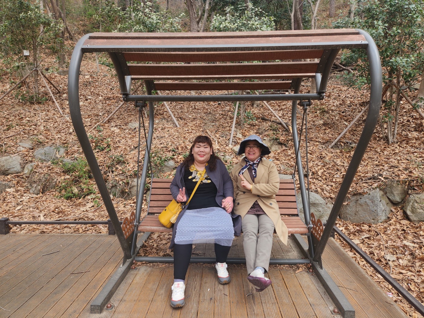두명의 당사자가 산책로에 있는 벤치에 앉아 밝은 표정으로 함께 찍은 사진입니다.