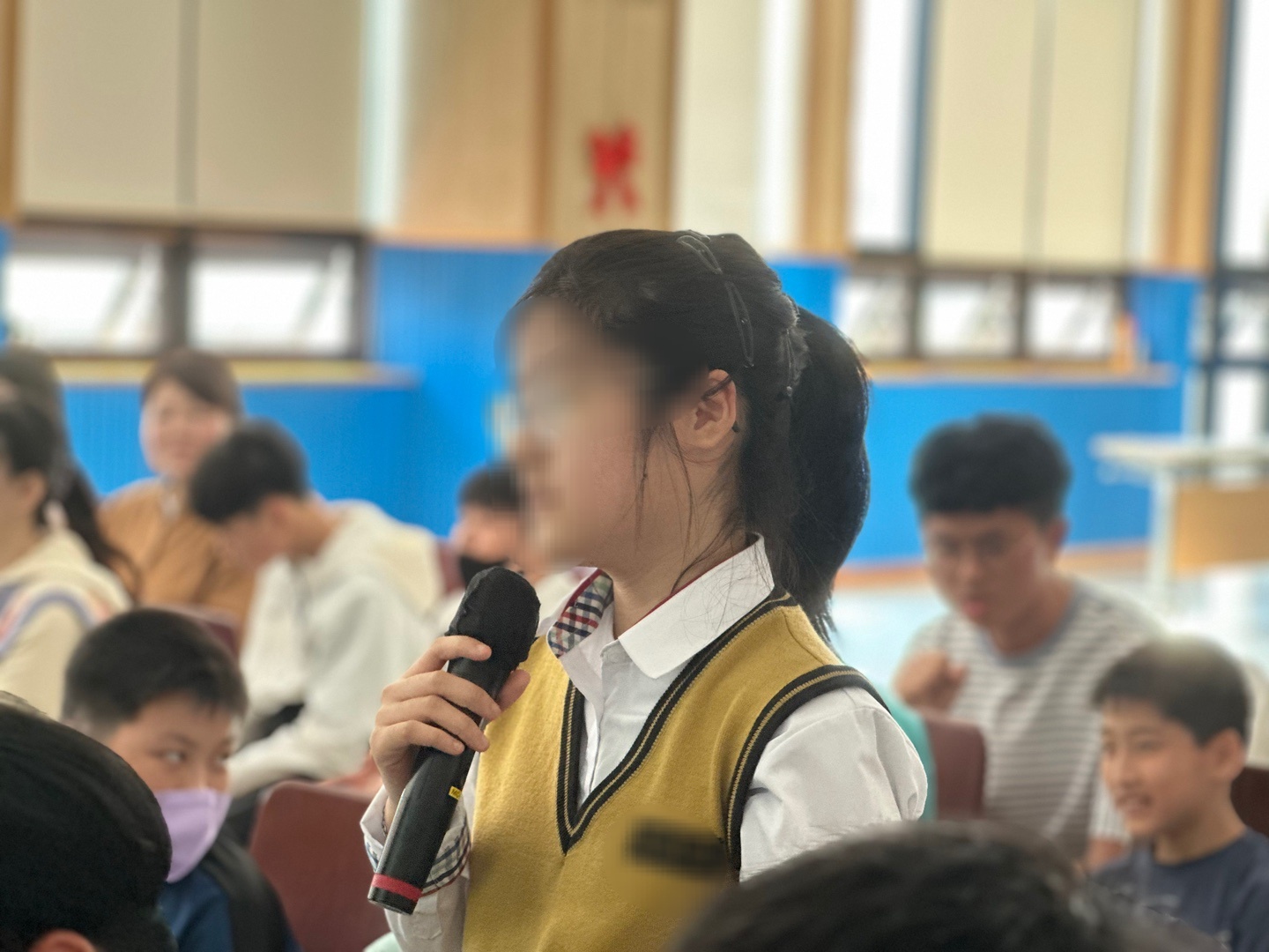 교복을 입은 여성 이용인이 일어나 마이크를 잡고 발표를 하고 있는 모습의 사진입니다. 