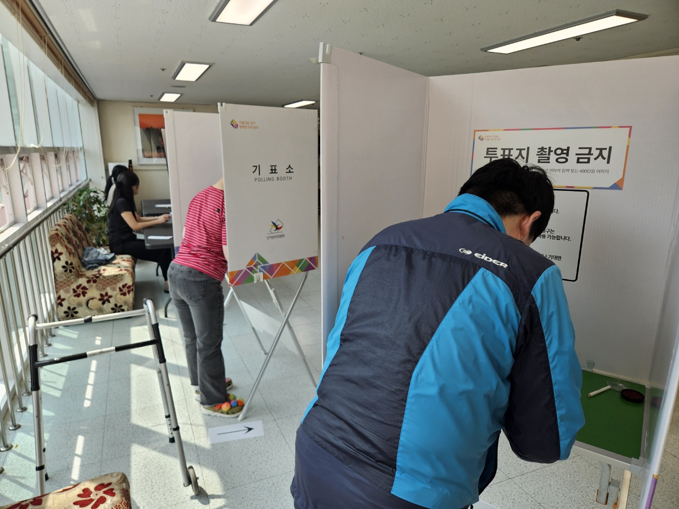 기표소 두 곳 안에서 각자 이용인 한명씩 들어가 투표를 하고 있는 뒷 모습입니다. 