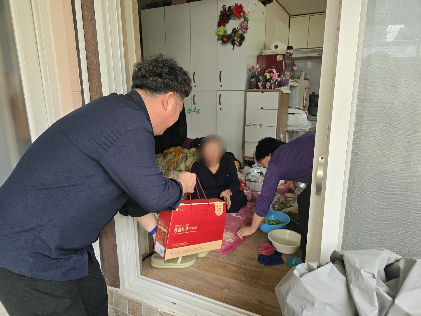 재가장애인 어르신 댁에 방문하여 건강식품을 전달하고 있는 담당 사회복지사의 모습입니다.