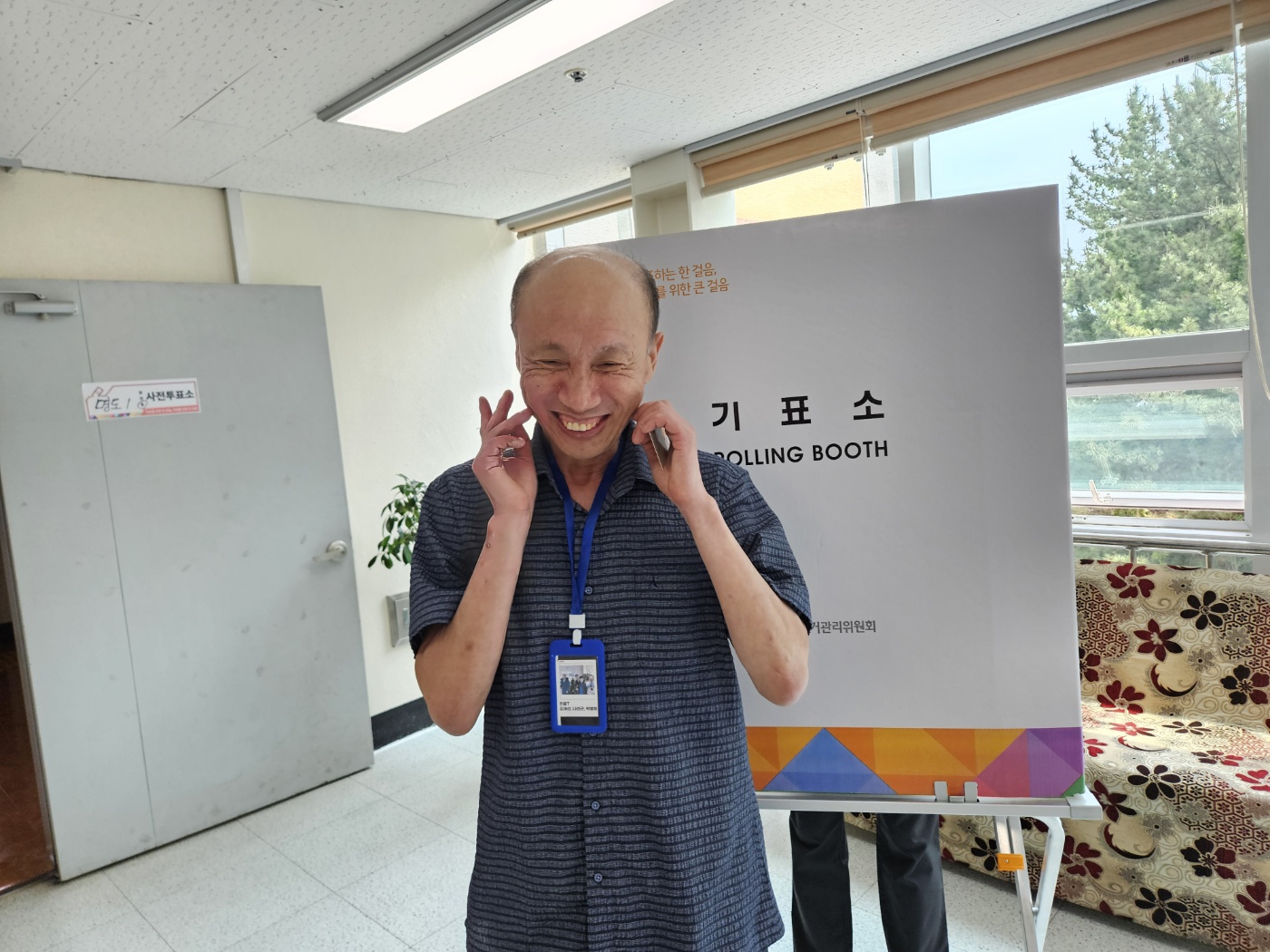 기표소 앞에서 활짝 웃는 표정으로 촬영한 이용인의 사진입니다. 