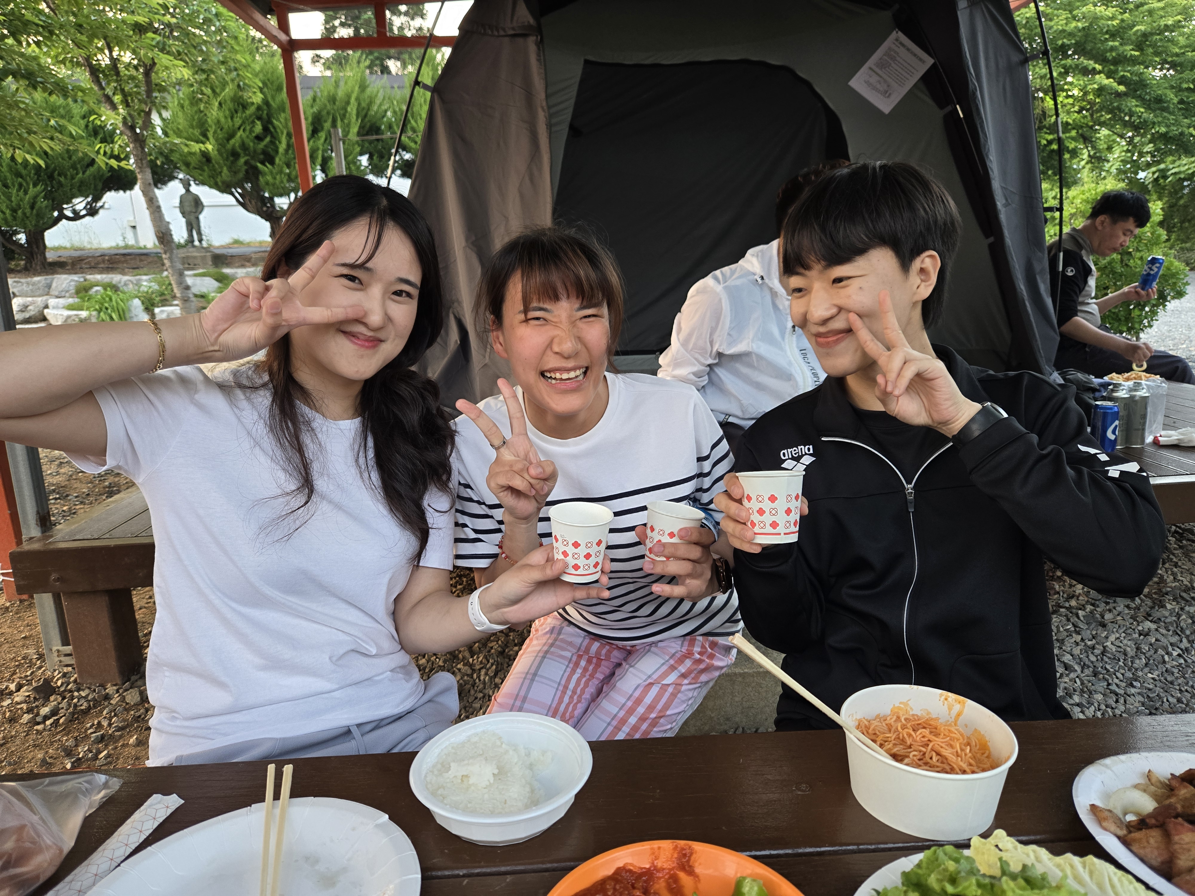 식사를 하며 음료컵을 들고 이용인 한명과 교사 두명이 함께 찍은 사진입니다. 사진속 인물들은 모두 밝은 표정을 짓고 있습니다. 