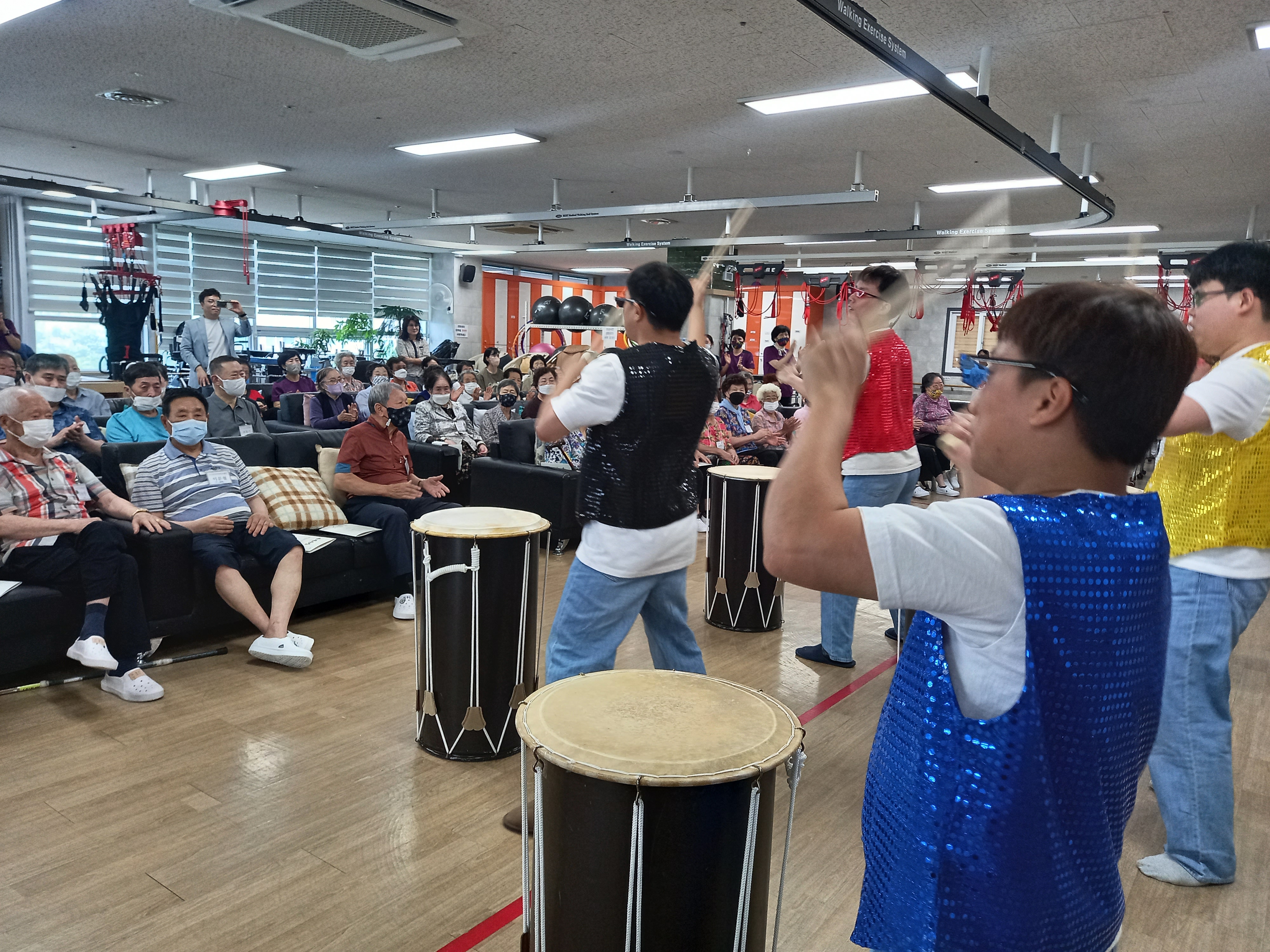 전남재활주간보호센터를 이용하는 분들이 관람석에 앉아있고 리듬공감팀이 난타공연을 하고 있는 사진입니다. 
