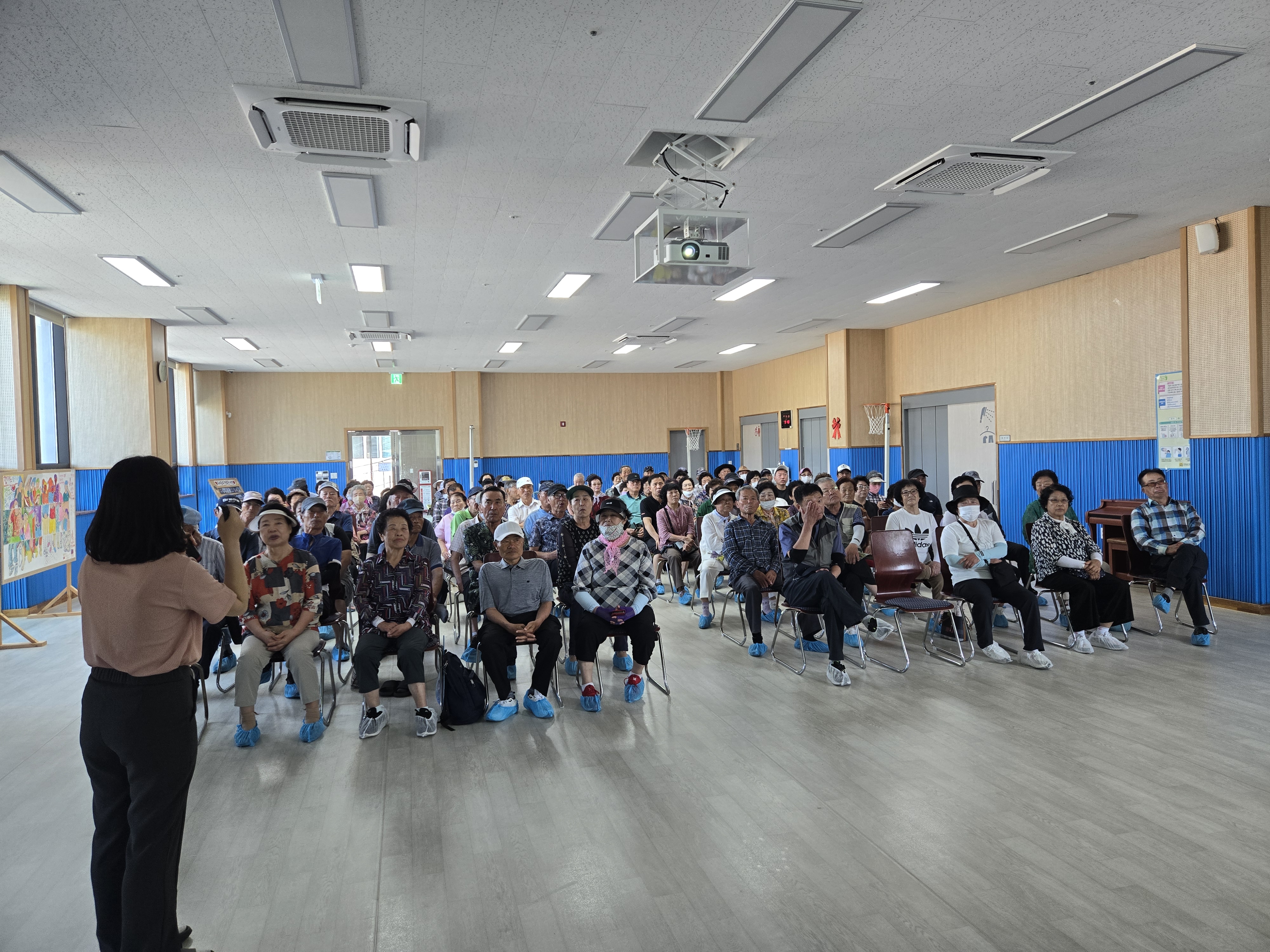 장애인일자리 사업 참여자들이 자리에 착석하여 담당직원의 설명을 집중해서 듣고 있는 모습입니다. 