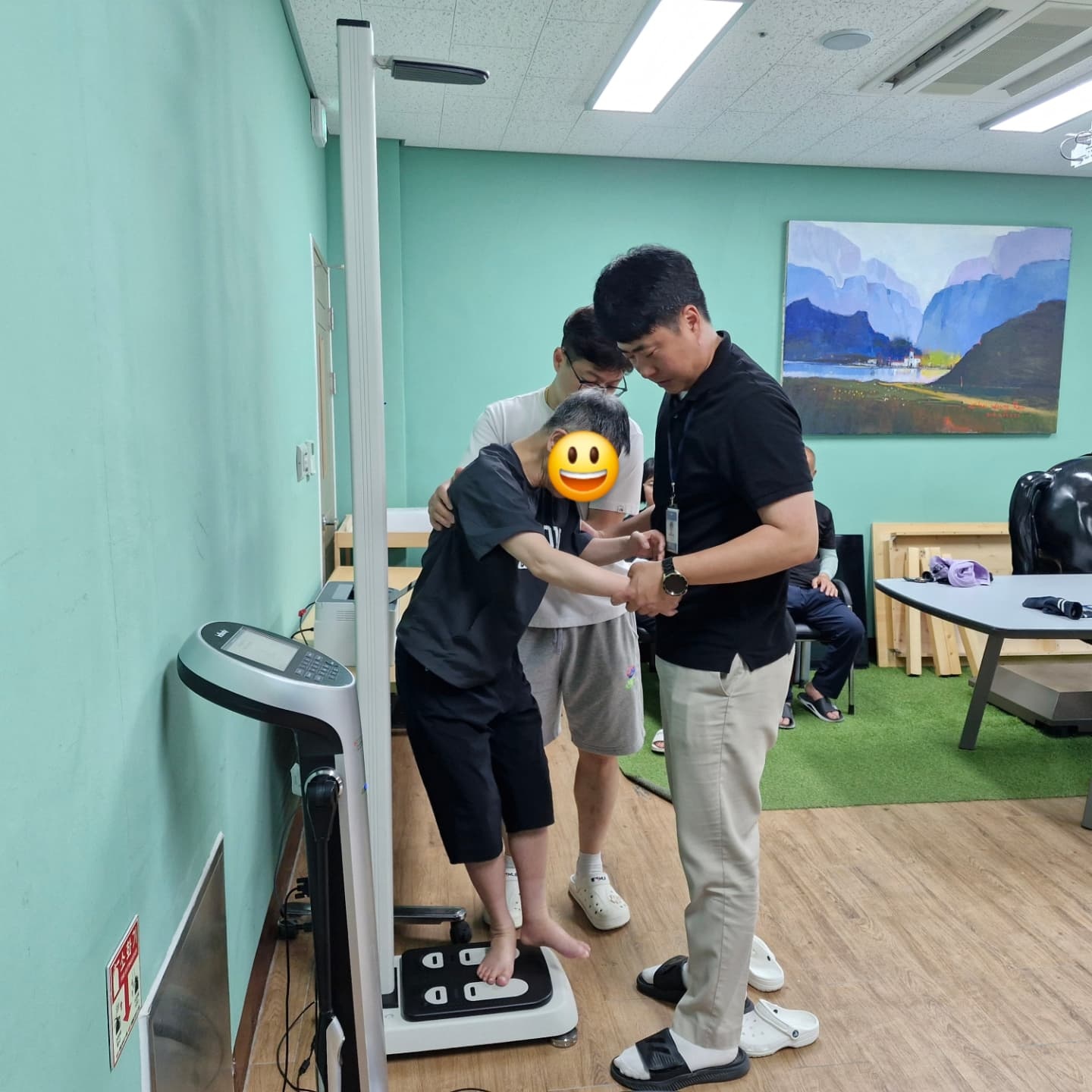 담당교사가 보담하우스 담당교사와 함께 이용인의 체중과 신장을 측정하고 있는 모습입니다.
