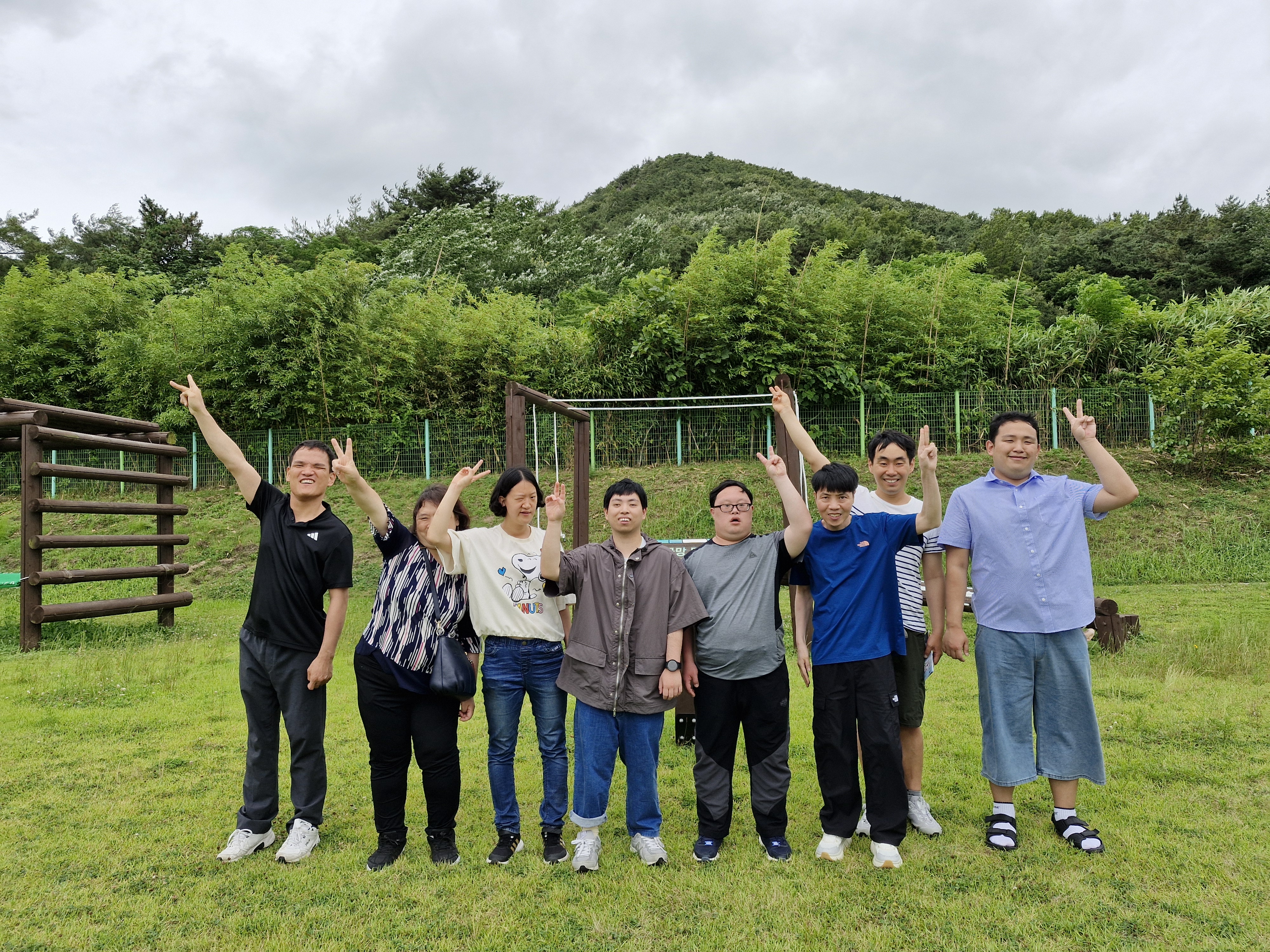 푸르른 잔디밭을 배경으로 이용인 8명이 함께 찍은 단체사진입니다. 