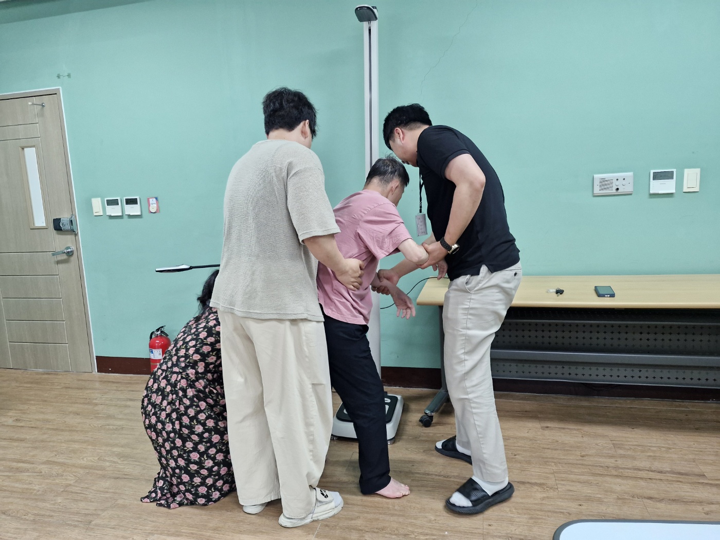 담당교사가 보담하우스 담당교사와 함께 이용인의 체중과 신장을 측정하고 있는 모습입니다.