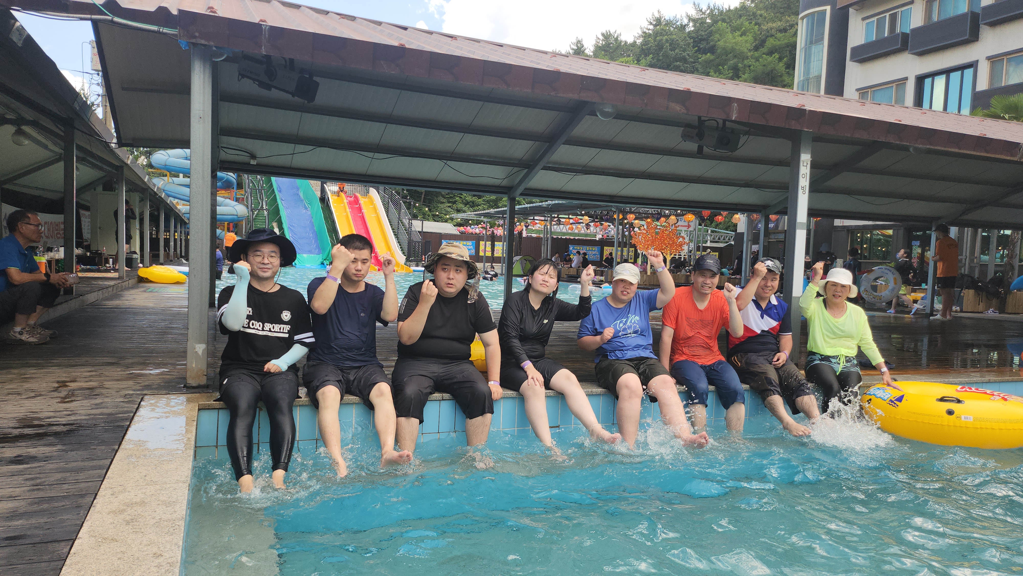 물놀이에 참가한 주간보호센터 이용인들과 교사가 한 곳에 앉아 단체사진을 찍은 모습입니다.