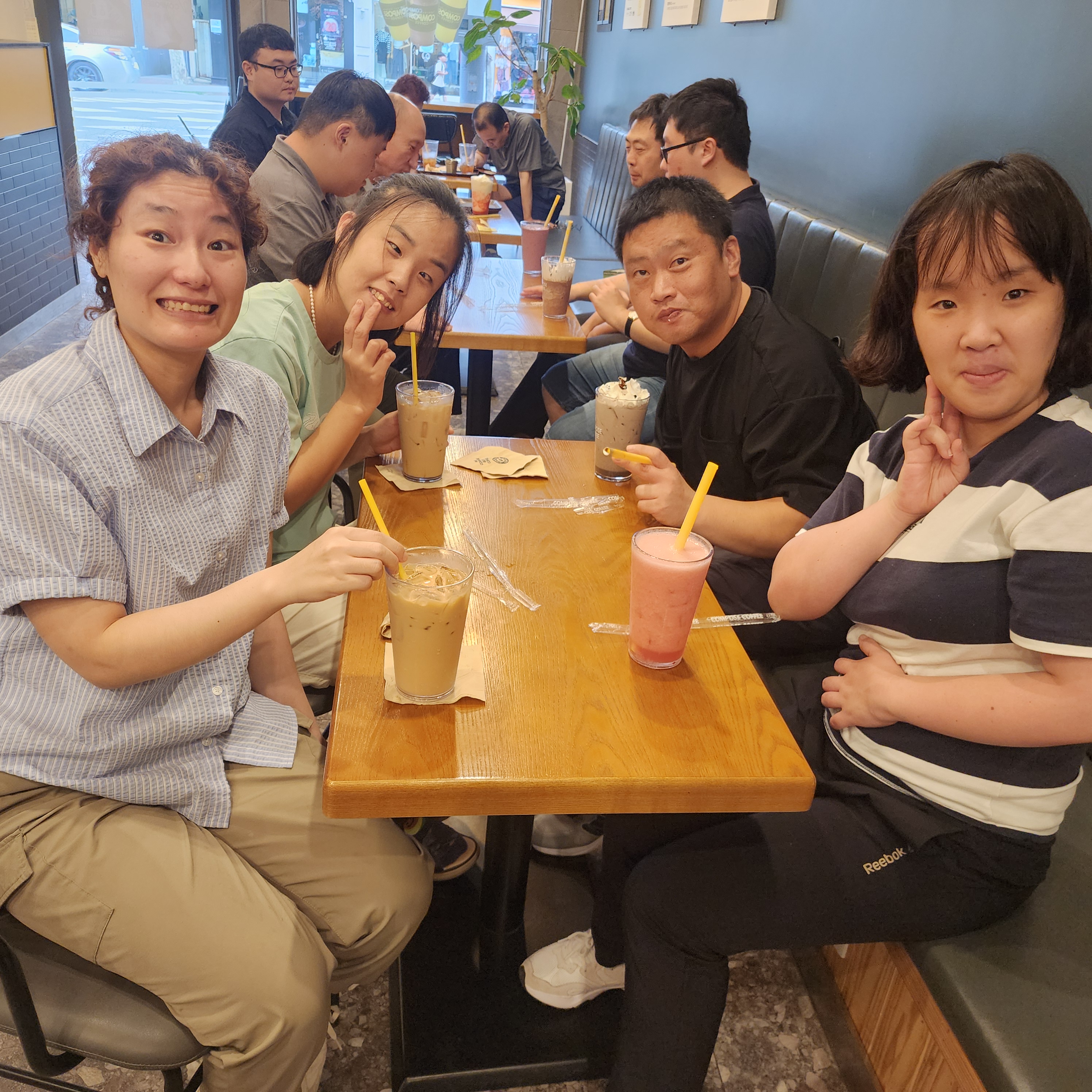 카페에서 음료를 마시며 카메라를 응시하는 이용인들의 사진입니다. 