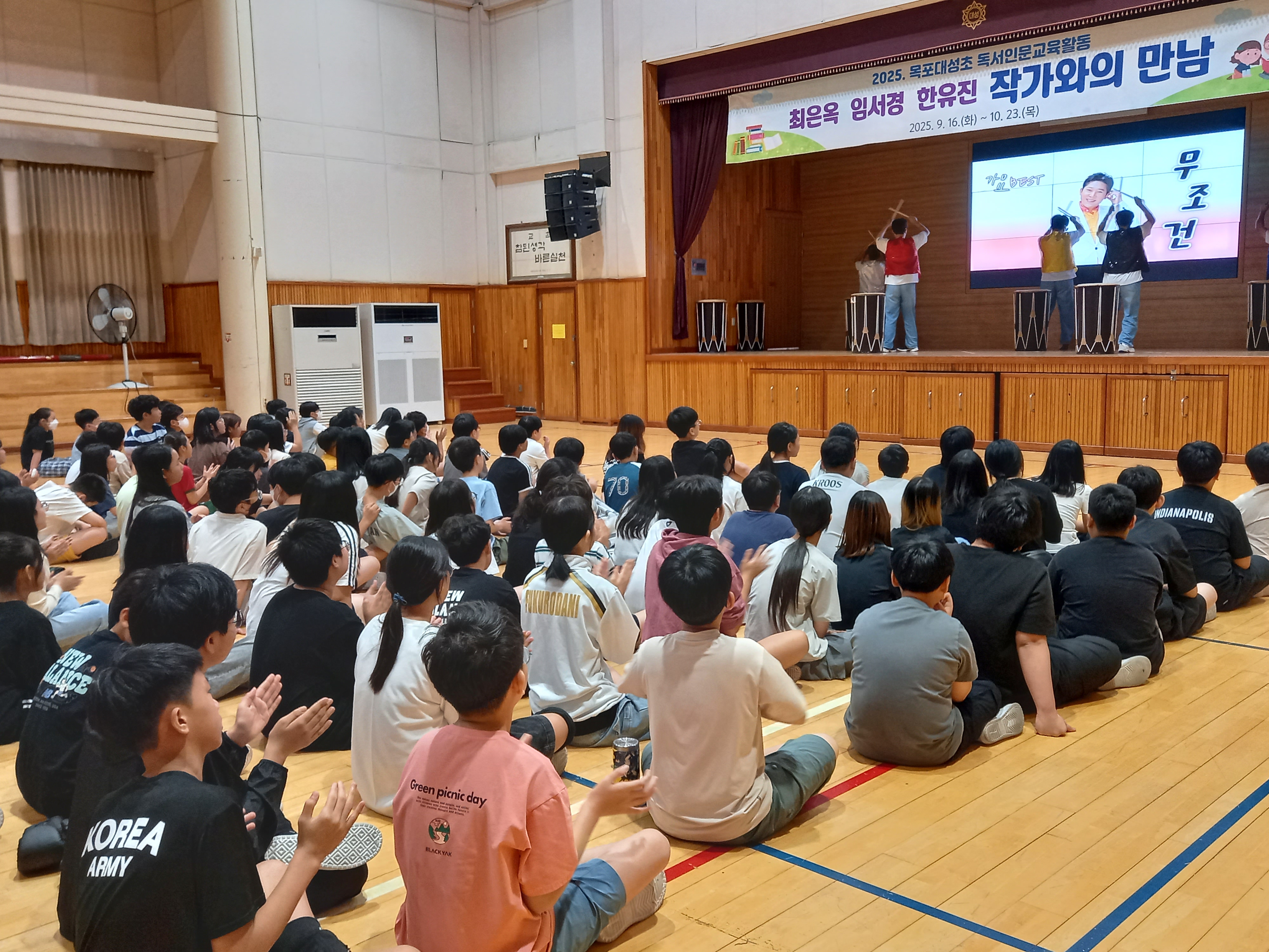 학교 강당에서 난타공연을 하고 있는 리듬공감팀의 사진입니다. 