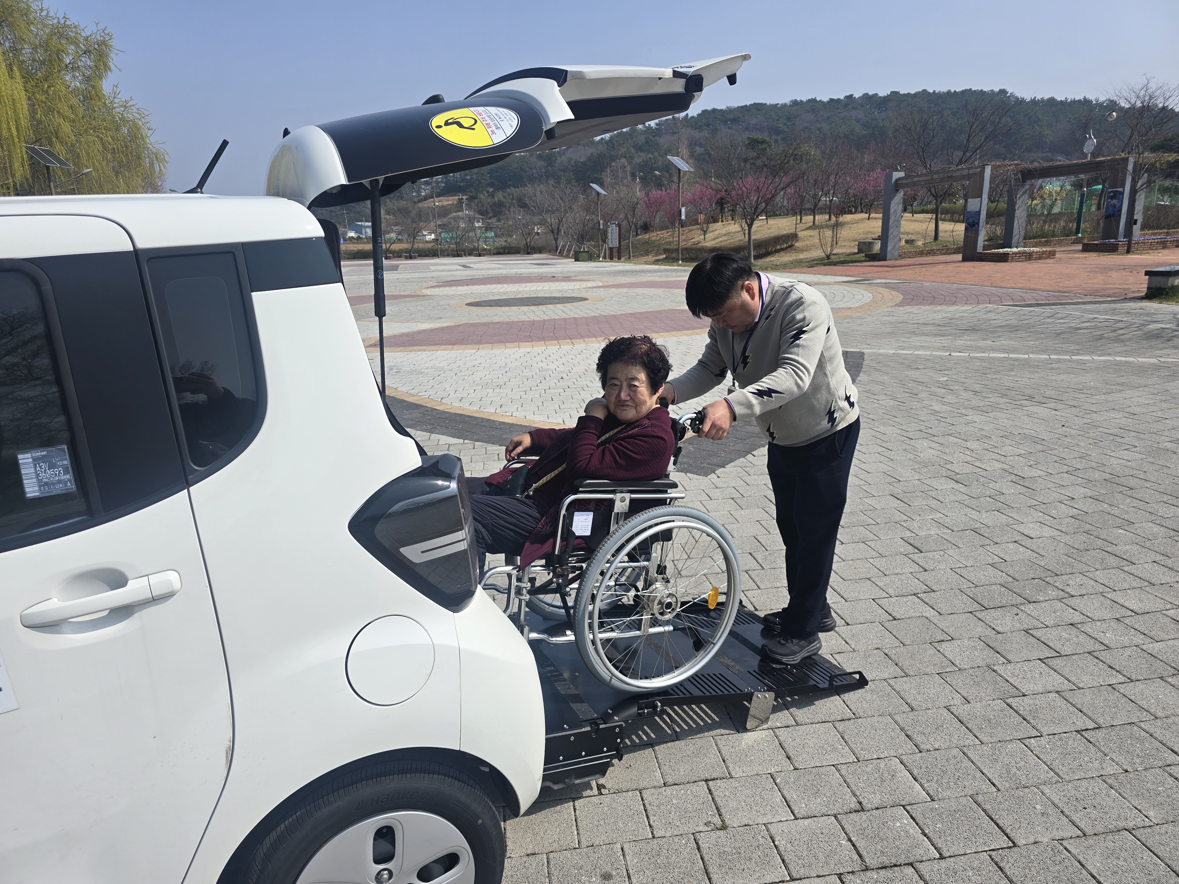 직원이 휠체어를 밀고 차에 타는 모습입니다.