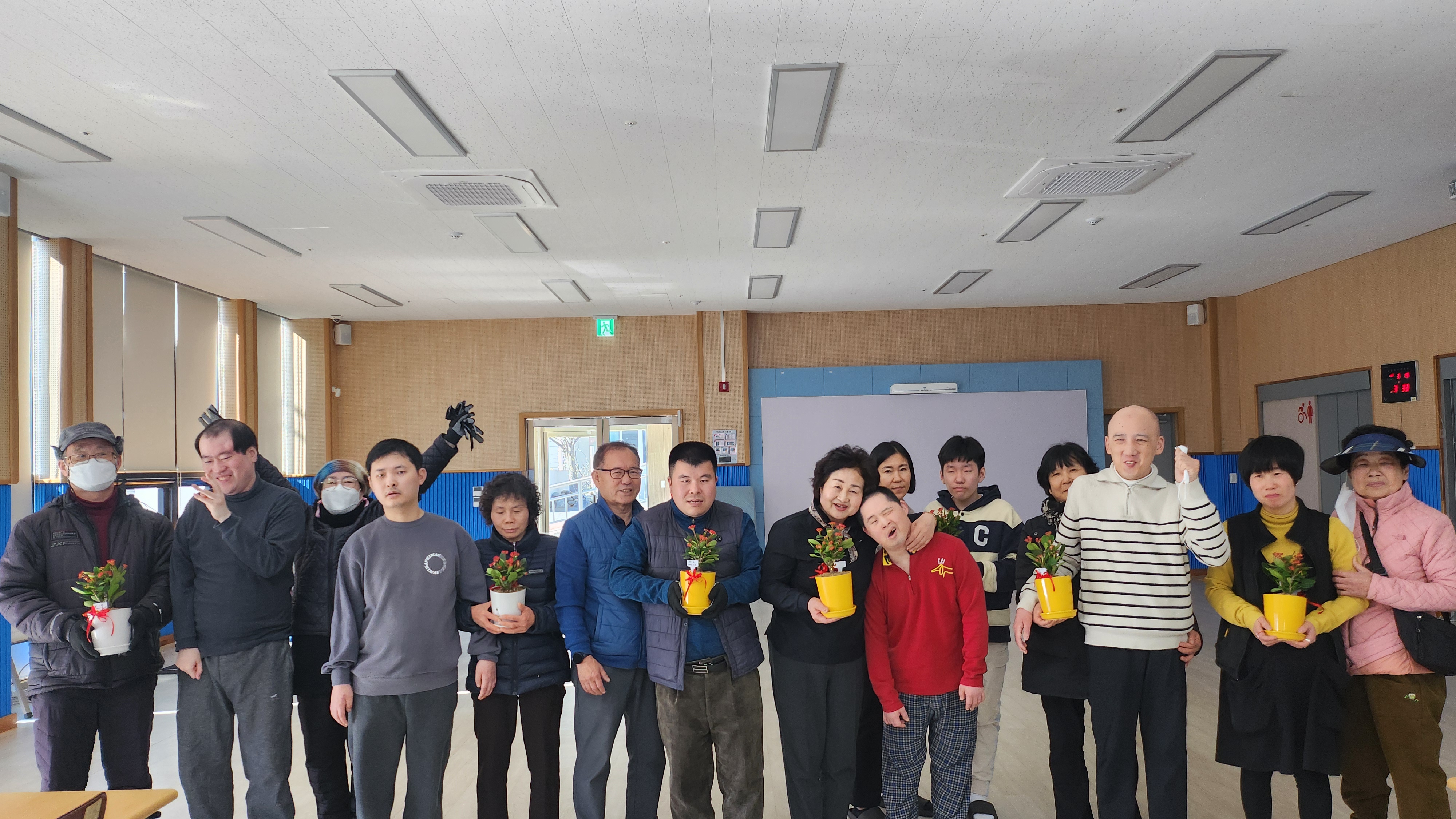 가족화분 만들기 활동을 마친 뒤, 모두 모여 직접 만든 화분을 들고 환하게 웃으며 사진을 찍는 모습입니다.