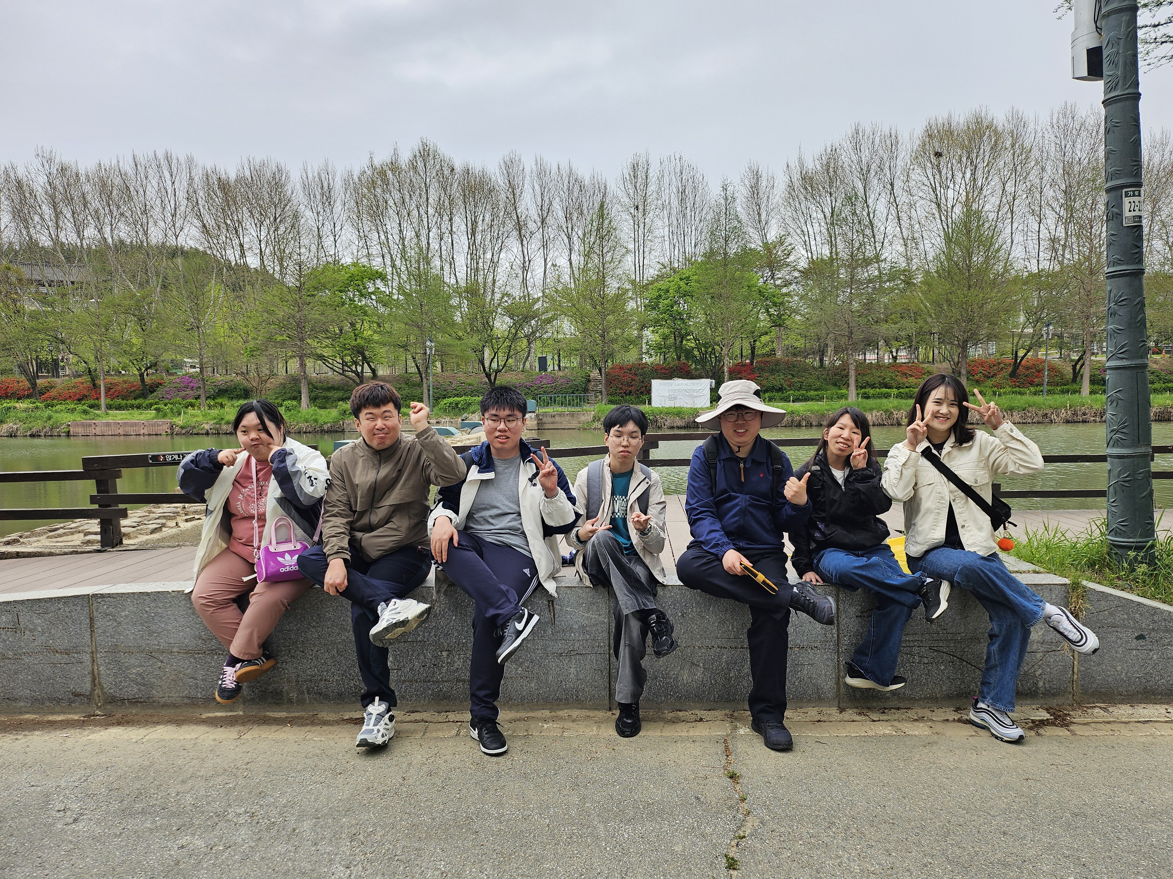 강가 앞에서 앉아서 같은 포즈를 하며 사진을 찍고있는 모습입니다.